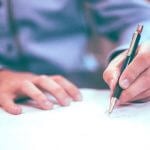 A student filling out papers with a pen.