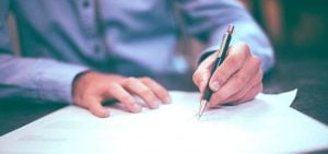 A student filling out papers with a pen.