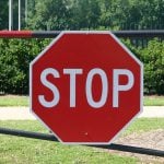 A big stop sign hanging on a pole.