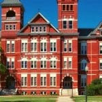 A red brick campus building with trees surrounding it.