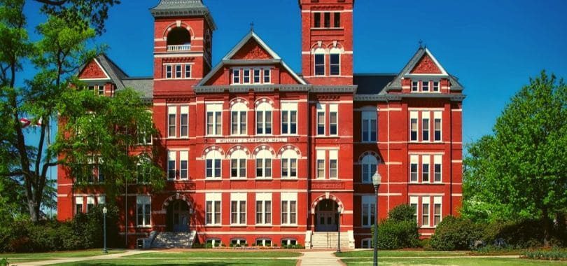 A red brick campus building with trees surrounding it.