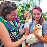 Two college students holding a duck at a campus event.