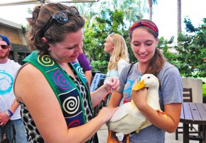 Two college students holding a duck at a campus event.