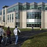 Four students walking towards the campus.