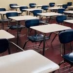 Rows of beige desks and blue chairs in a high school.