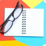 A pair of glasses sitting on top of a journal.