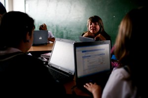 A teacher guiding her students in a technical education class using their laptops.