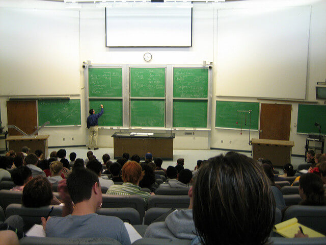 Students sitting a classroom while a professor lectures.