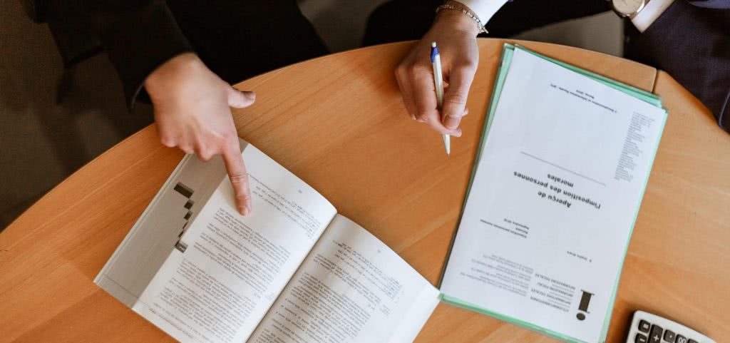 A school counselor pointing at a book while a student takes notes.