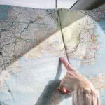 A person holding and pointing at a paper map.