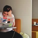 A high school student sitting with their laptop, looking frustrated.