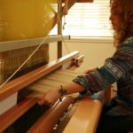 A lady knitting fabric using a manual machine.