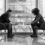 Two college counselors sitting together on their laptops.