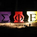 The Sigma Phi Epsilon letters on colorful boxes, illuminated by a spotlight.