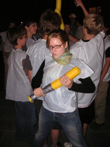 Student holding a foam bat with other students behind her.
