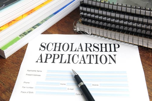 Scholarship application form surrounded by pens and notebooks.