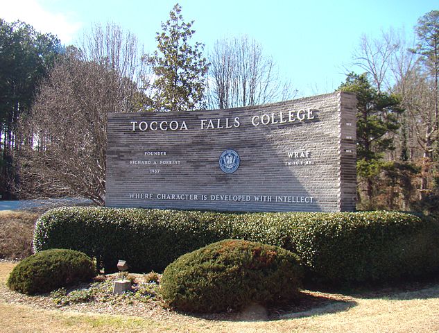 Toccoa Falls College entrance sign surrounded with manicured bushes and trees.