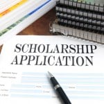 Scholarship application form surrounded by pens and notebooks.