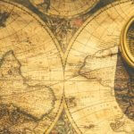 A compass sitting on a map of the world.