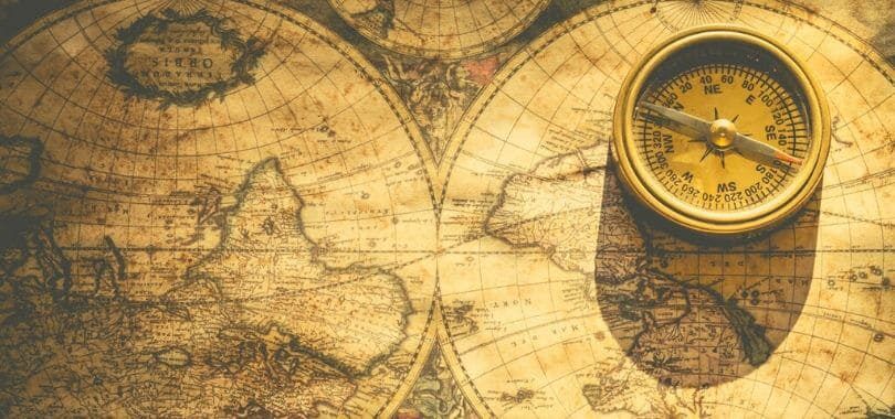 A compass sitting on a map of the world.