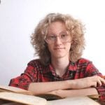 A student sitting at a table surrounded by books.