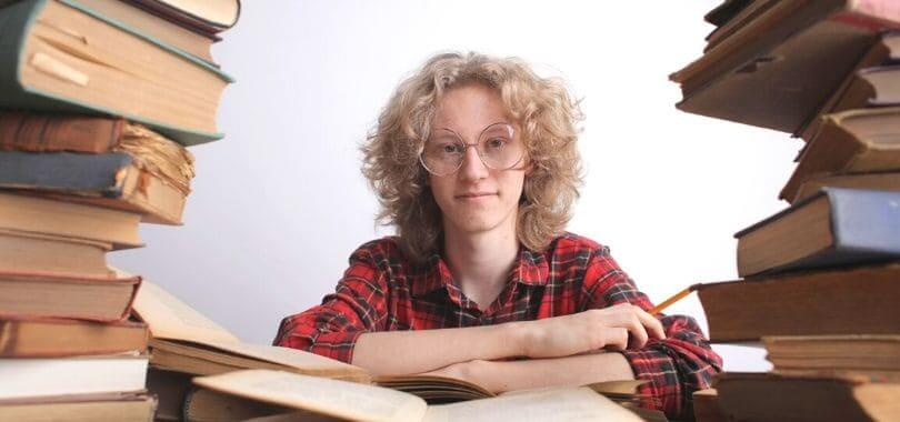 A student sitting at a table surrounded by books.