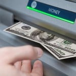 Photograph of a person withdrawing money from an ATM.