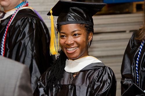A girl graduate student is smiling and looking far away.