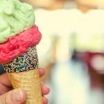 A person holding an ice cream cone with two scoops of ice cream.