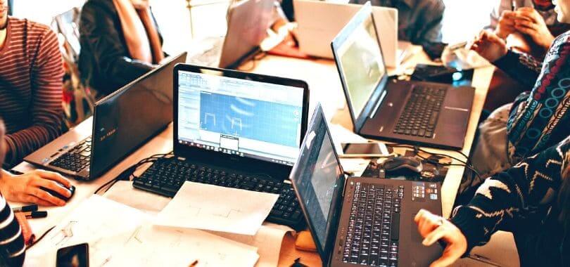 A group of people sitting together at a table with their laptops.