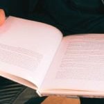 A student holding a textbook open.