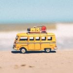 A small, yellow toy beach van at the beach.