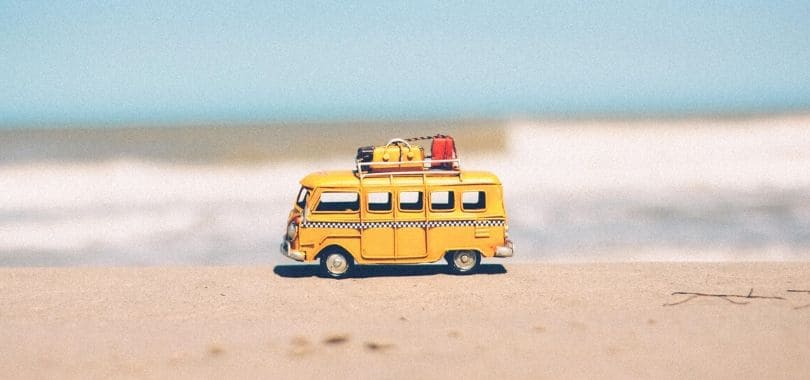 A small, yellow toy beach van at the beach.