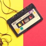 A cassette tape with the tape pulled out, against a yellow and red background.