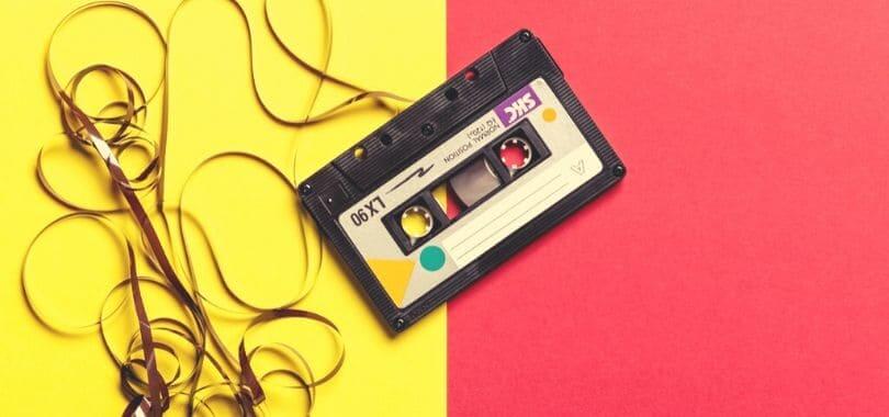 A cassette tape with the tape pulled out, against a yellow and red background.