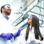 A group of scientists in white lab coats talking to each other.