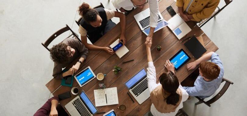 People sitting at a table, with two people shaking hands.