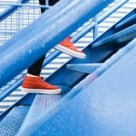 A person is wearing red shoes going up in a blue stair.