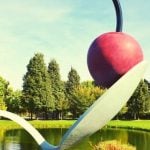 A sculpture of a cherry on top of a spoon.