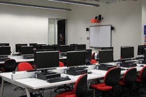 Computer laboratory with red chairs and desktops.
