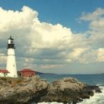 A lighthouse in Maine next to the ocean.