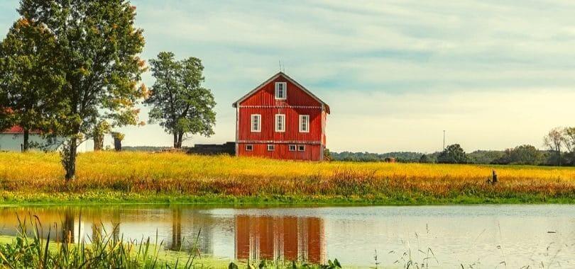 A red barn with a small pond in front of it.