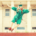 College student wearing a green graduation robe jumping.