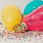 Colorful balloons laying together on top of confetti.
