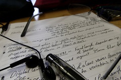 Earbuds, pen, and eyeglass sitting atop college notes.
