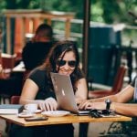 Three college students sitting at a table with a laptop and notebooks.