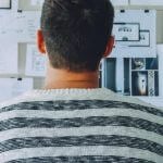 Student standing in front of a wall with papers covering it.