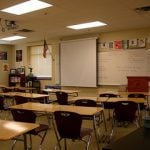 An empty classroom with desks, chairs and white board.