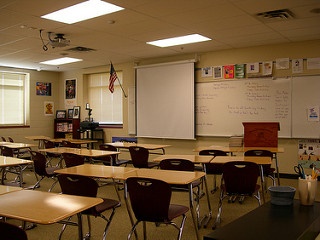 An empty classroom with desks, chairs and white board.