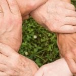 Multiple people's hand grabbing another person's wrist to form a ring.